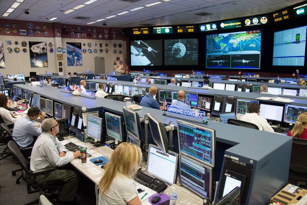 Mission Control Center at NASA's Johnson Space Center with federal and contractor employees at work.